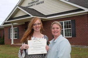 Kim Whitlock (left) and Lisa McKinney (right) stand in front of the Fairmount Community Center. Whitlock was the first student to earn a GED® diploma from the Adult Education Center located inside the building and McKinney was her instructor.